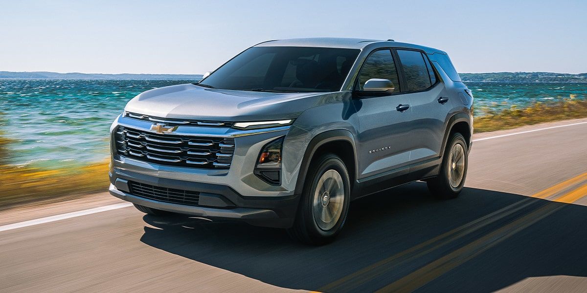 Chevrolet Equinox 2026 gris en conduite sur une route au bord de l’eau.