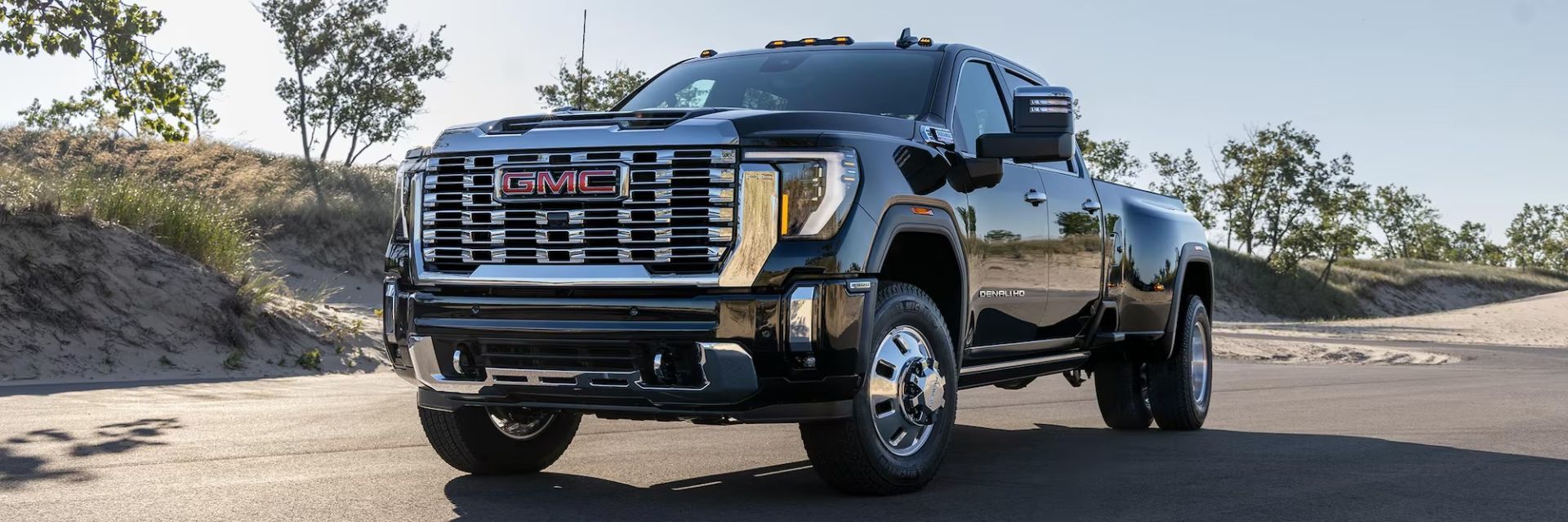 GMC Sierra 3500 Denali HD 2026 noir brillant garé sur une route sablonneuse, démontrant sa puissance.