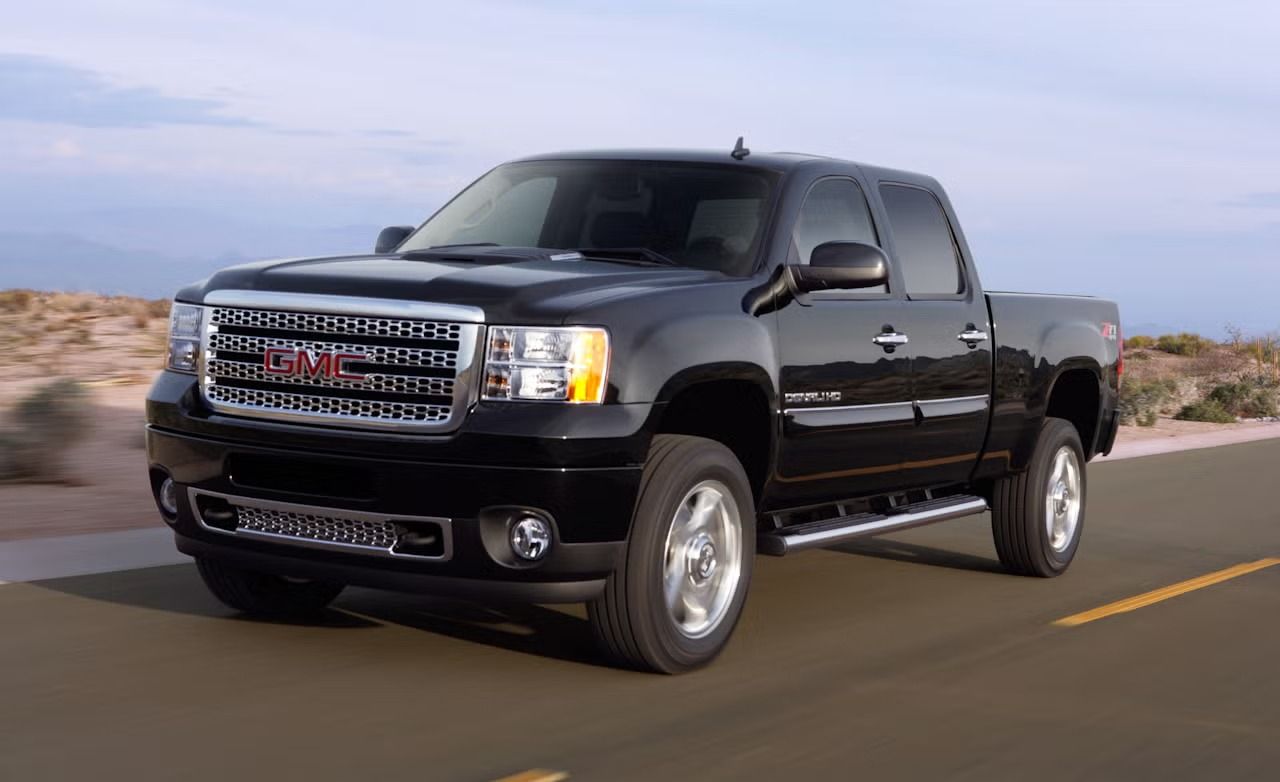 GMC Sierra HD 2011 Denali noir roulant sur une route désertique, démontrant la durabilité des modèles HD.