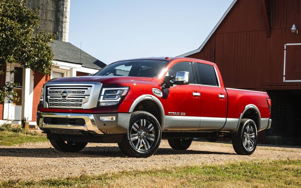 Nissan Titan 2020 rouge garé devant une grange, illustrant un camion usagé puissant et bien entretenu.