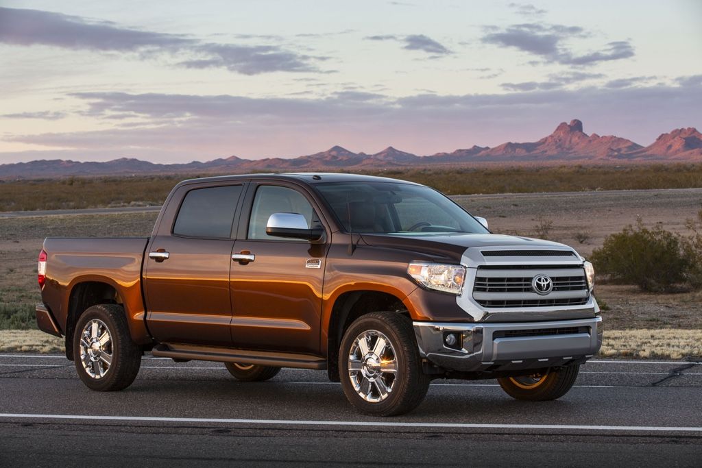 Toyota Tundra 2014 brun stationné sur la route au lever du soleil, symbole de fiabilité et de performance à long terme.